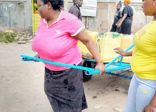 woman pictured pulling a loaded 'Mkokoteni' gets help from well-wishers