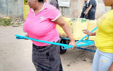 woman pictured pulling a loaded 'Mkokoteni' gets help from well-wishers