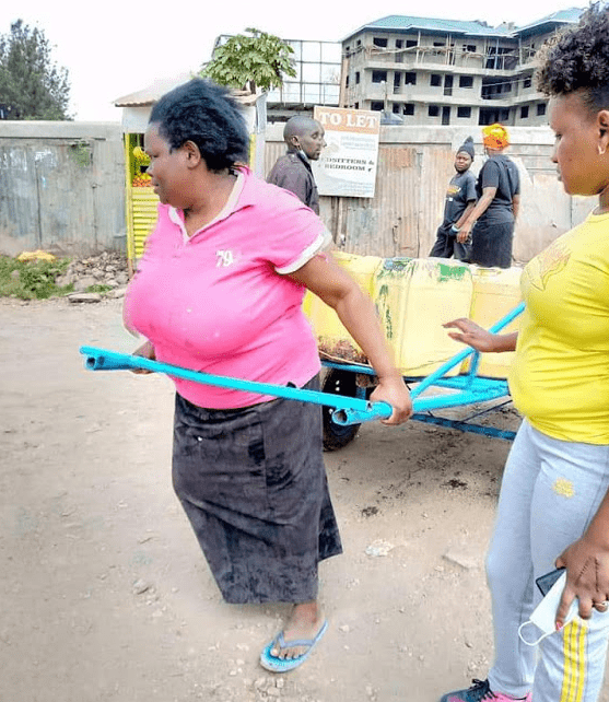 woman pictured pulling a loaded 'Mkokoteni' gets help from well-wishers